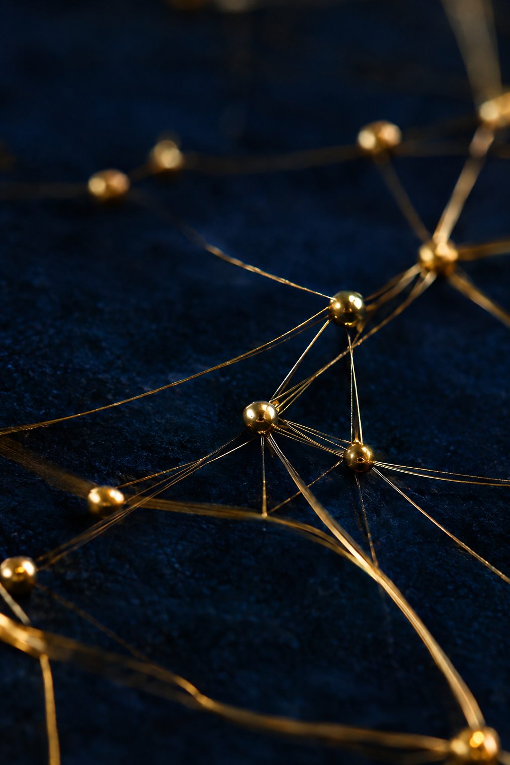 Gold threads connecting brass nodes on navy — a metaphor for connected systems